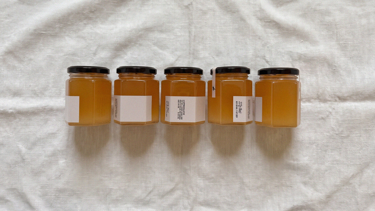 Five glass jars filled with golden honey.